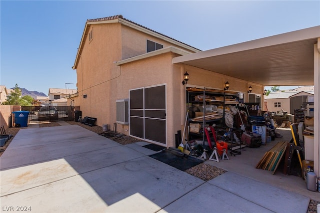 back of house with a gate, fence, and stucco siding