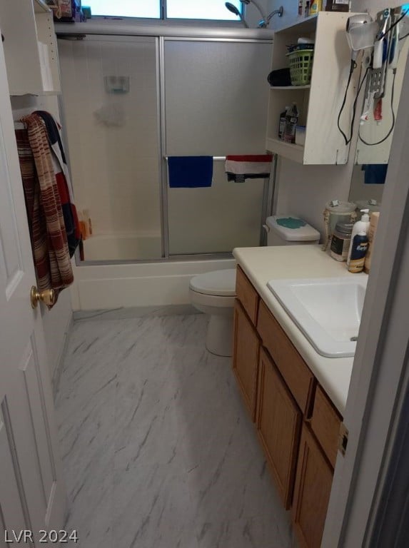 full bathroom with combined bath / shower with glass door, toilet, and vanity