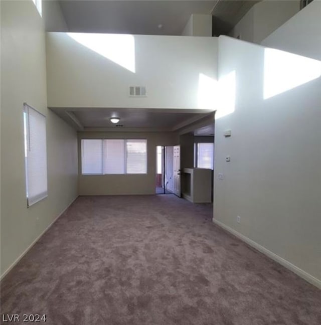 carpeted empty room with a high ceiling