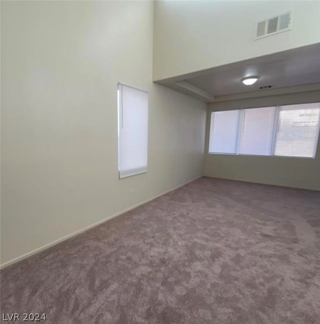 unfurnished room featuring carpet floors and a towering ceiling