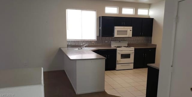 kitchen with light tile floors, kitchen peninsula, tasteful backsplash, white appliances, and sink