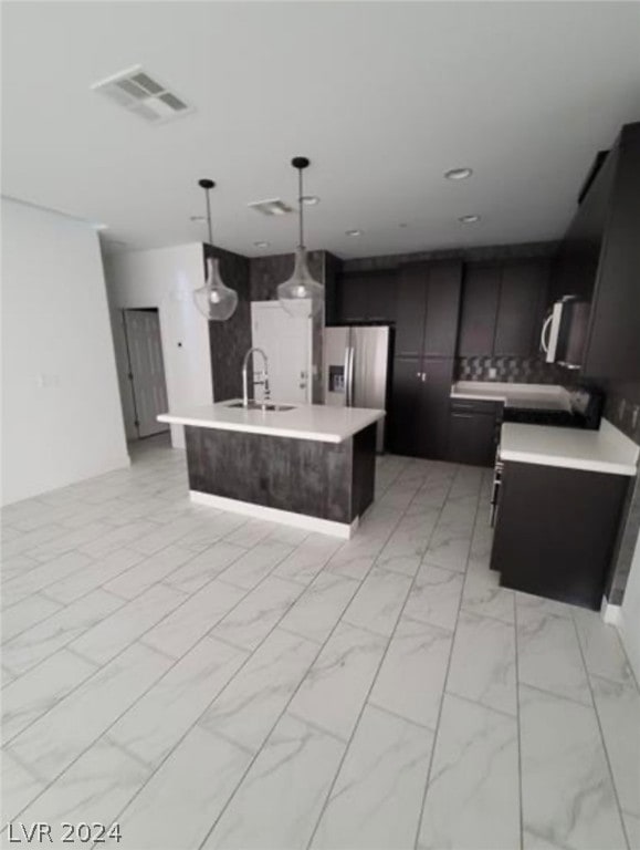 kitchen with light tile floors, a center island with sink, decorative light fixtures, and sink