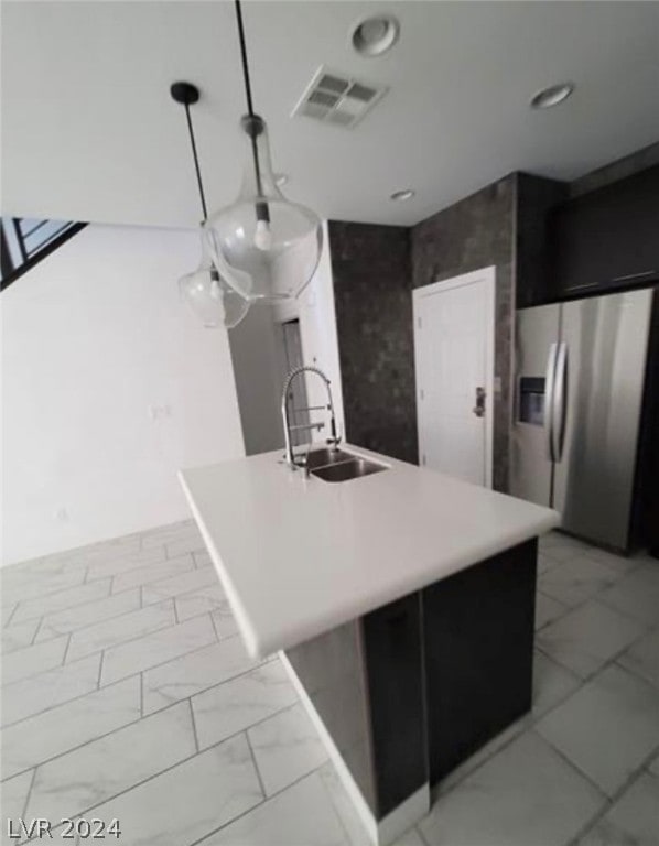 kitchen featuring decorative light fixtures, light tile floors, a kitchen island, stainless steel fridge with ice dispenser, and sink