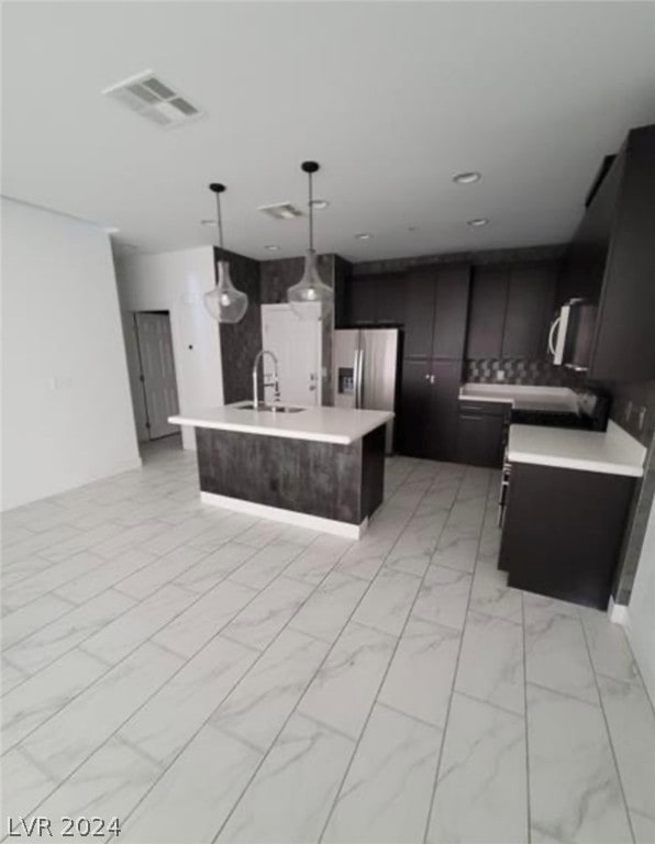 kitchen with stainless steel fridge with ice dispenser, a center island with sink, hanging light fixtures, and light tile floors