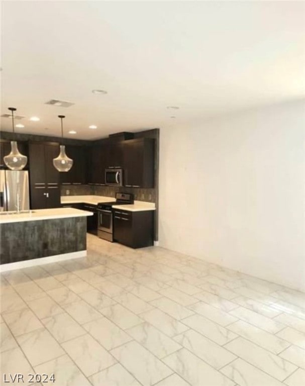 kitchen with hanging light fixtures, stainless steel appliances, and light tile floors