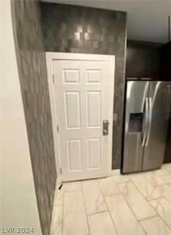 interior space with stainless steel fridge with ice dispenser and light tile floors