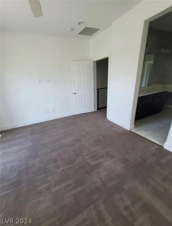 interior space with ceiling fan and dark colored carpet