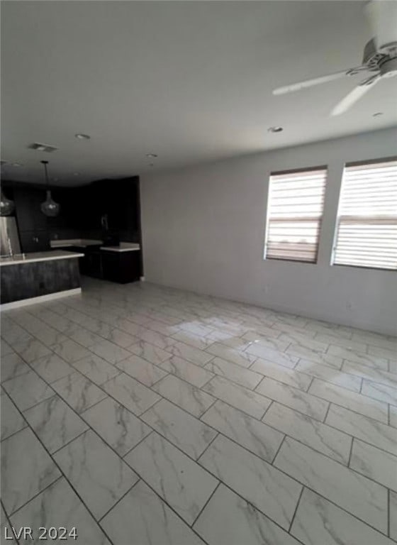 unfurnished living room featuring light tile flooring and ceiling fan