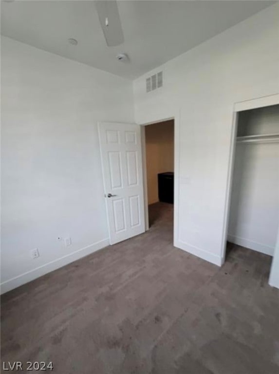 unfurnished bedroom with a closet and dark carpet