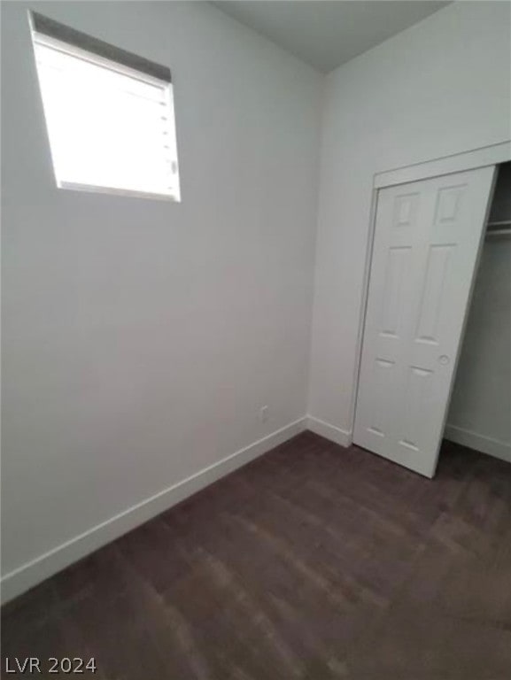 unfurnished bedroom featuring dark hardwood / wood-style floors and a closet