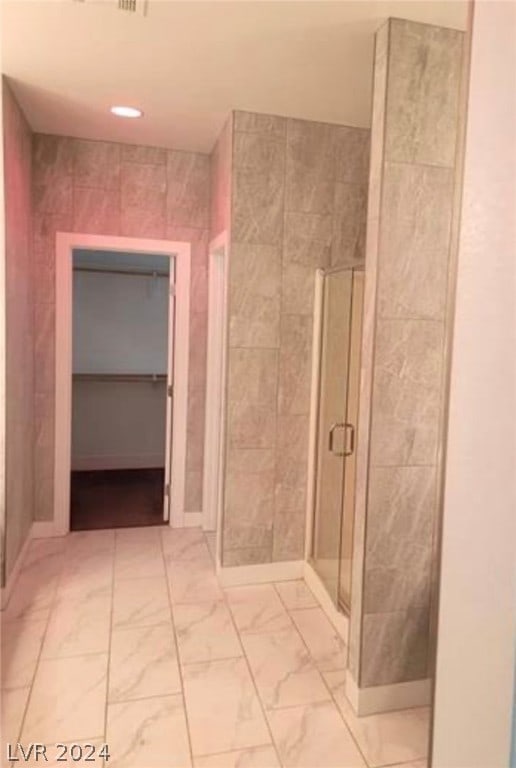 bathroom with a shower with door and tile flooring