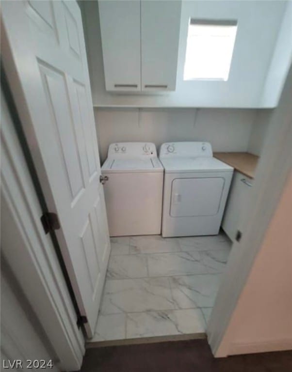 clothes washing area with light tile flooring, separate washer and dryer, and cabinets