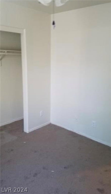 unfurnished bedroom featuring a closet and dark colored carpet