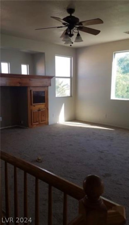 unfurnished living room featuring ceiling fan and carpet flooring