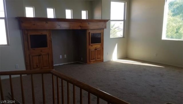 unfurnished living room featuring carpet floors and a wealth of natural light