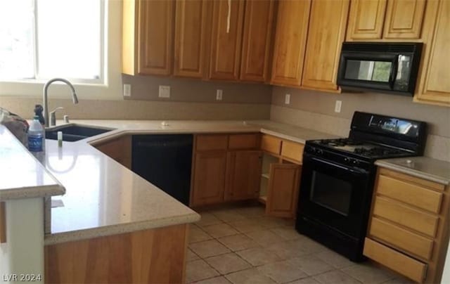 kitchen featuring light stone counters, light tile floors, black appliances, and sink