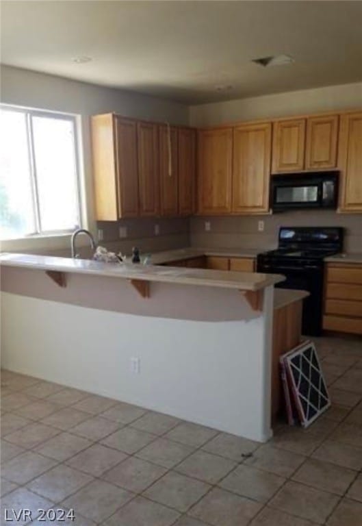 kitchen featuring light tile floors and black appliances