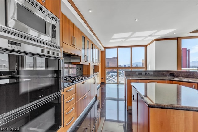 kitchen featuring light tile patterned floors, appliances with stainless steel finishes, backsplash, a kitchen island, and sink