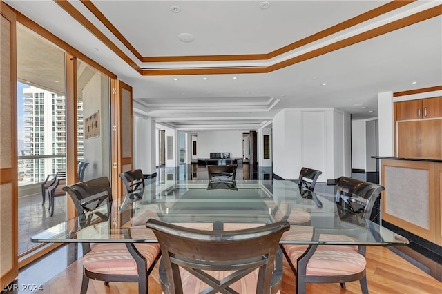 dining space featuring a raised ceiling, wood-type flooring, and ornamental molding