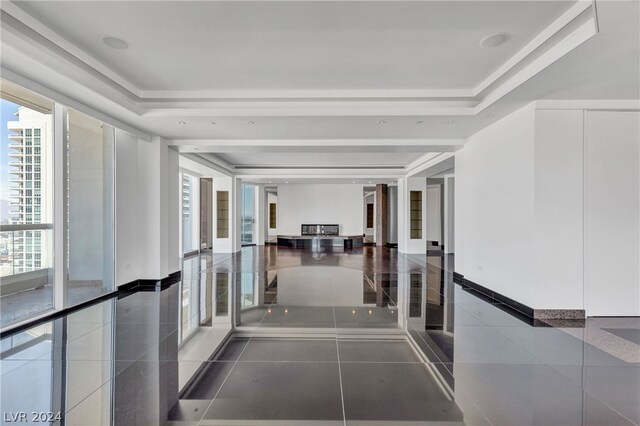 corridor with dark tile patterned floors and a tray ceiling