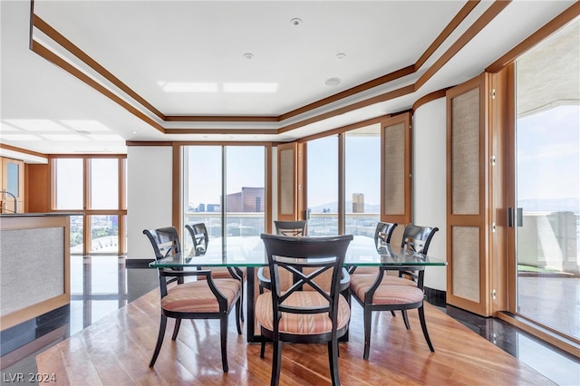 dining space featuring a wall of windows, ornamental molding, hardwood / wood-style flooring, and a tray ceiling