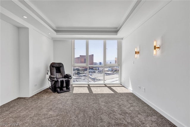 living area featuring ornamental molding, carpet flooring, and a raised ceiling