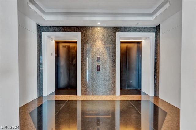 hall featuring a tray ceiling and elevator