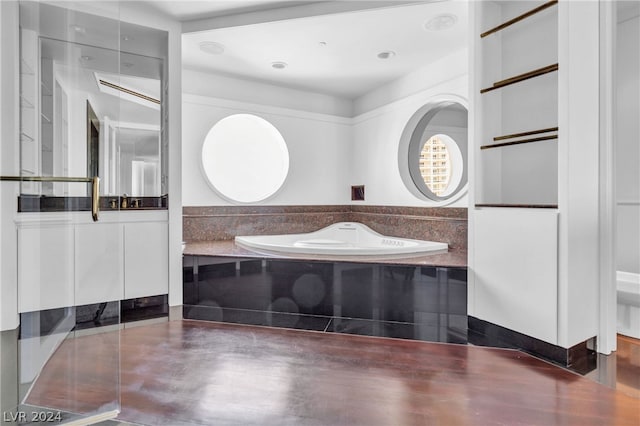 bathroom with vanity and tiled bath