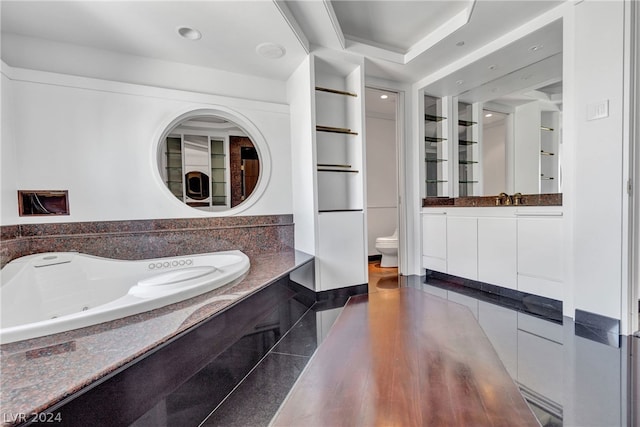 bathroom featuring vanity, a tub, hardwood / wood-style flooring, and toilet