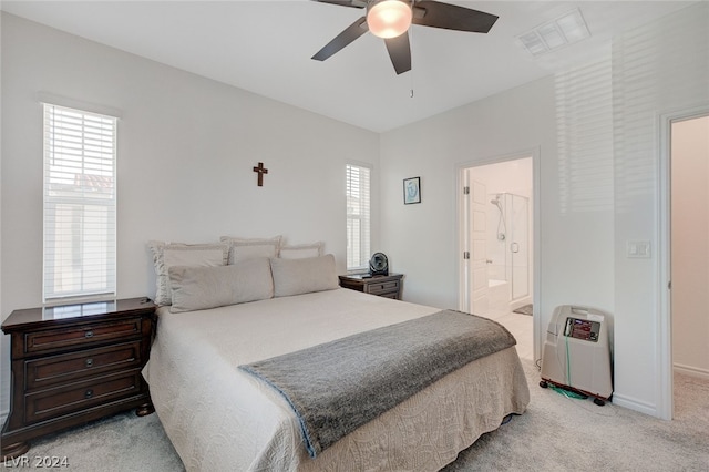 bedroom featuring ceiling fan, light colored carpet, and ensuite bathroom