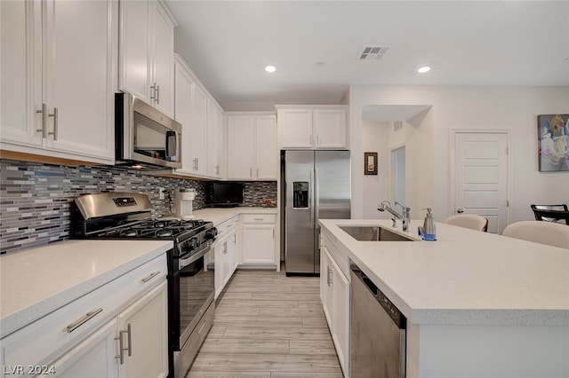 kitchen with white cabinets, appliances with stainless steel finishes, tasteful backsplash, and sink