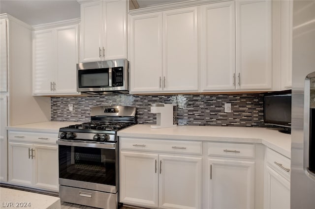 kitchen with backsplash, stainless steel appliances, and white cabinetry