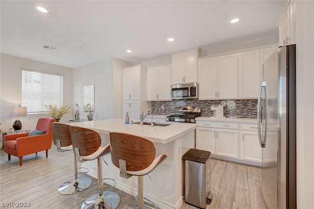 kitchen with a center island with sink, white cabinetry, appliances with stainless steel finishes, backsplash, and sink