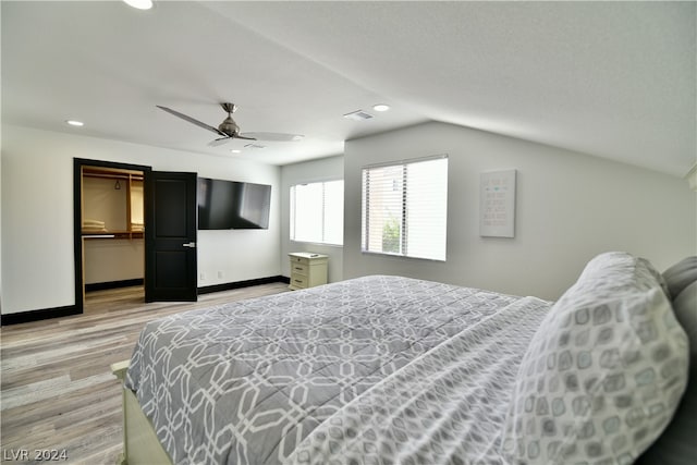 bedroom featuring vaulted ceiling, ceiling fan, a closet, light hardwood / wood-style flooring, and a spacious closet