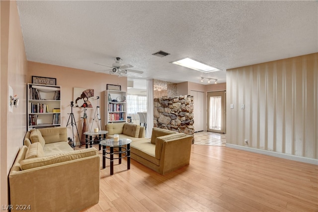 living room featuring a textured ceiling, ceiling fan, and light wood-type flooring