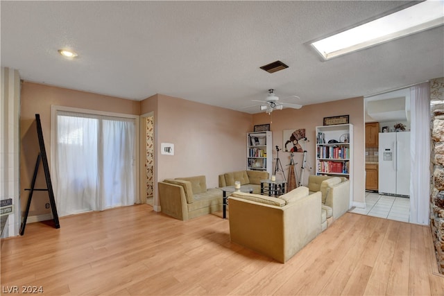 living room with a textured ceiling, ceiling fan, and light hardwood / wood-style floors