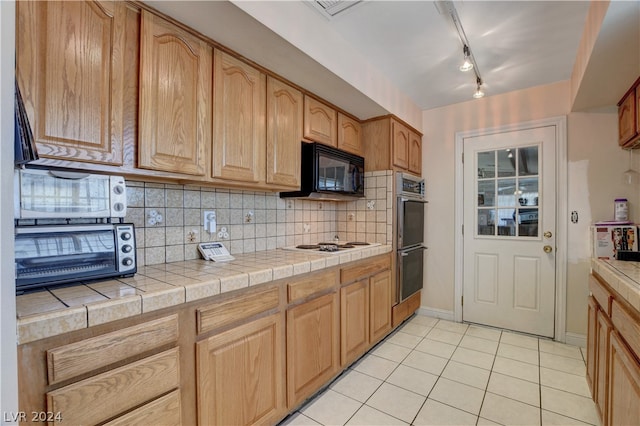 kitchen with rail lighting, tile counters, backsplash, and double oven