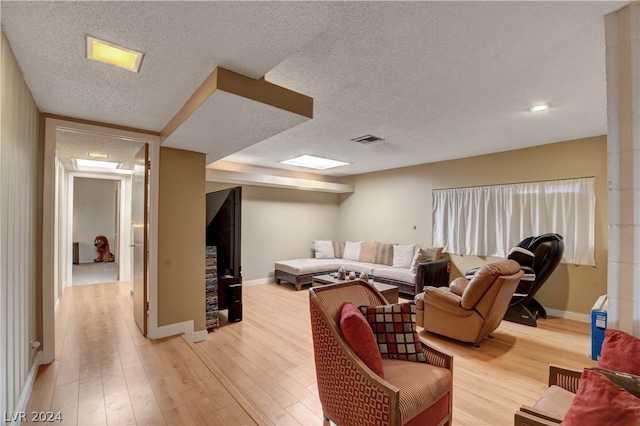 living room featuring light wood-type flooring and a textured ceiling