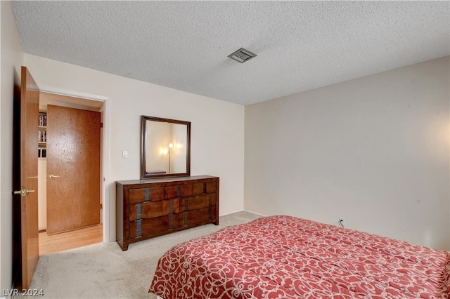 bedroom featuring light colored carpet and a textured ceiling