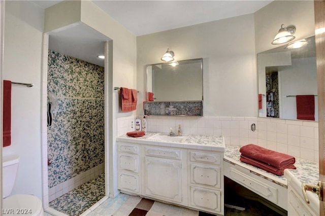 bathroom featuring a tile shower, backsplash, toilet, vanity, and tile floors