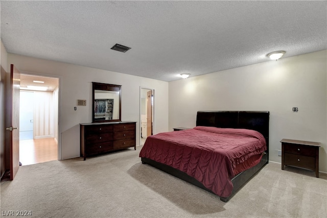 carpeted bedroom with ensuite bath and a textured ceiling