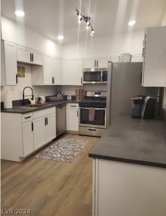 kitchen with white cabinetry, light hardwood / wood-style flooring, appliances with stainless steel finishes, and sink