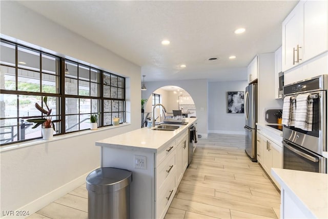 kitchen featuring white cabinetry, stainless steel appliances, sink, and a center island with sink