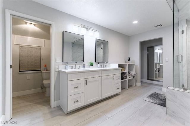 bathroom with vanity, a shower with shower door, wood-type flooring, and toilet