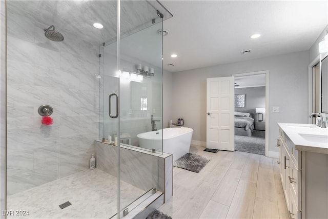 bathroom featuring hardwood / wood-style flooring, vanity, and plus walk in shower