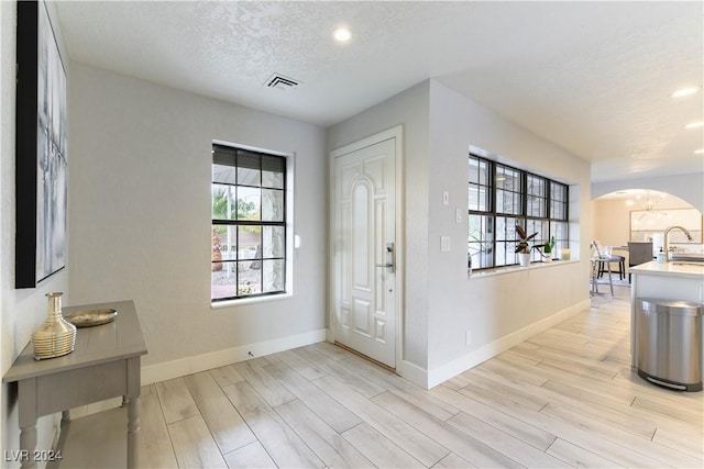 entryway featuring sink, light hardwood / wood-style floors, and a textured ceiling