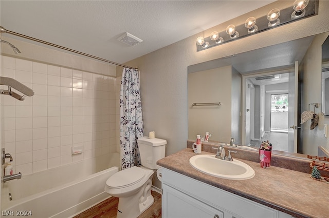 full bathroom with toilet, vanity with extensive cabinet space, shower / bath combination with curtain, wood-type flooring, and a textured ceiling