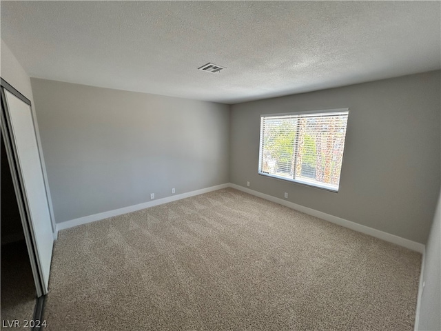 carpeted spare room featuring a textured ceiling