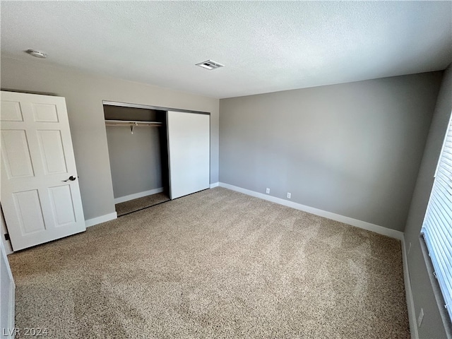 unfurnished bedroom with light carpet, a closet, and a textured ceiling