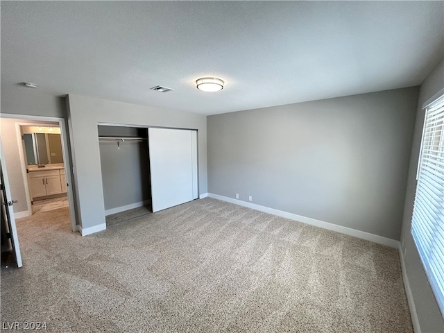 unfurnished bedroom featuring light colored carpet and a closet